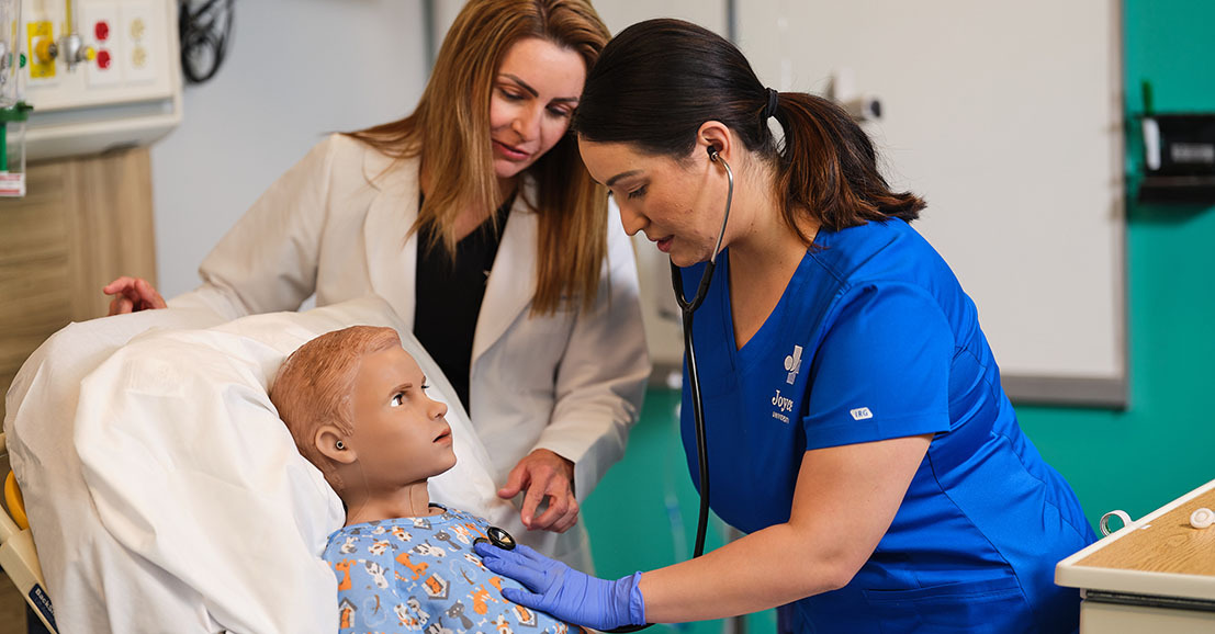 joyce university faculty teaching nursing student to check heart beat on pediatric patient mannequin