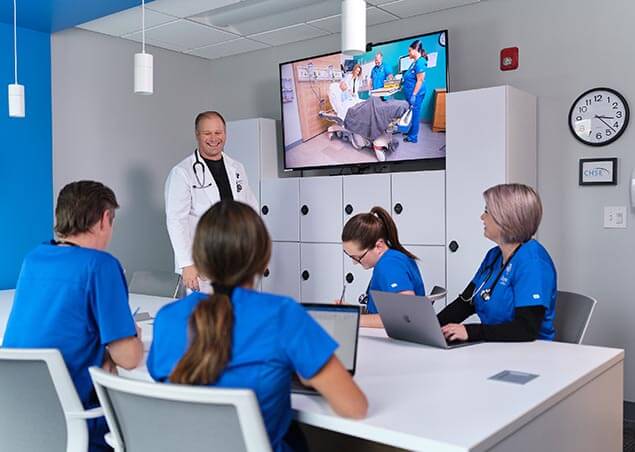 Joyce University students and instructor learning in the simulation debriefing room