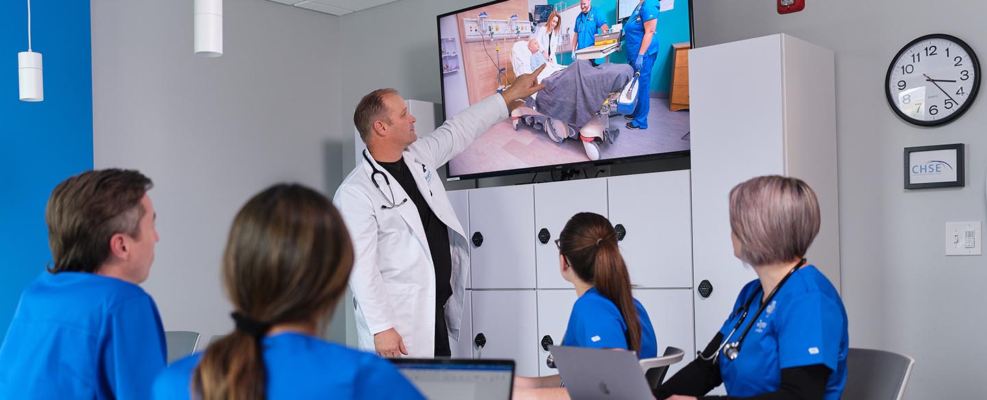 Joyce University instructor teaching four students in debriefing room at Joyce Johnson simulation center