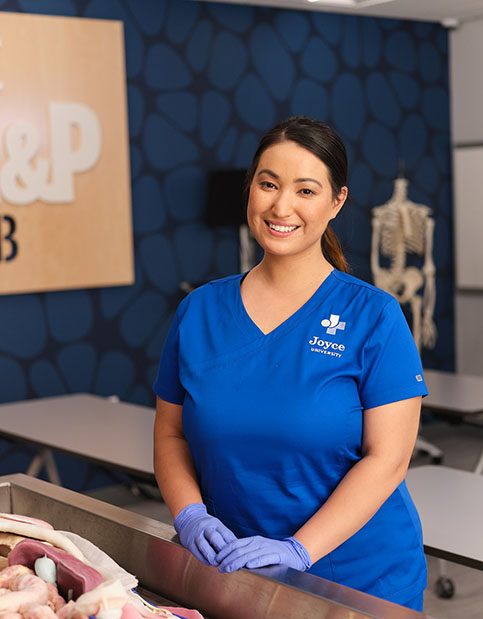 Joyce University nursing student in blue scrubs in a and p lab