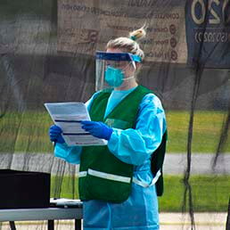 Joyce University student in personal protective equipment holding clipboard at covid-19 testing site