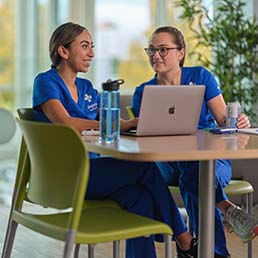 Joyce University students in blue scrubs studying at campus study center