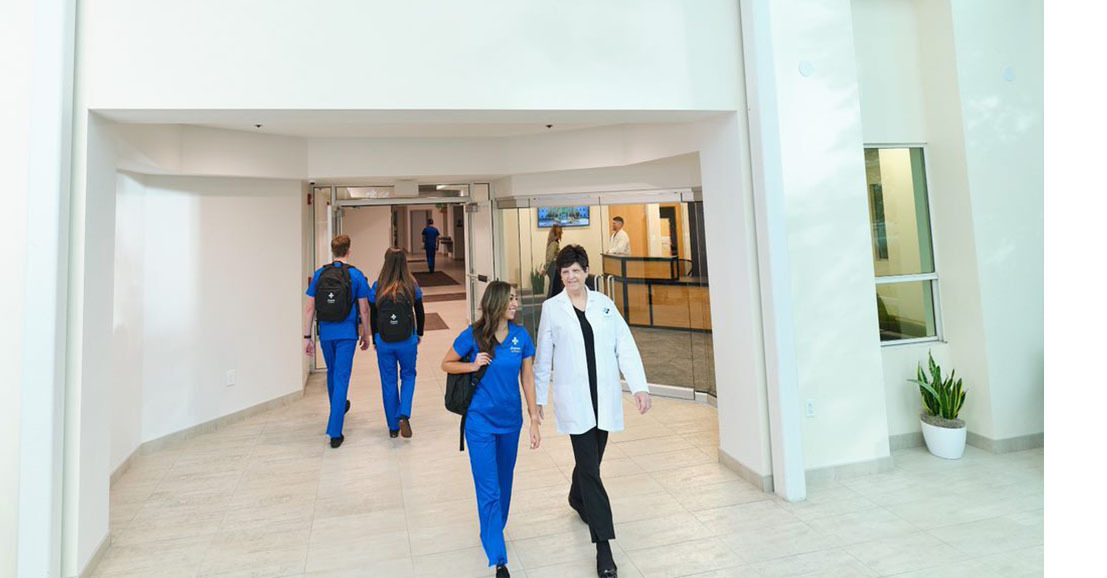 Joyce University faculty walking with nursing student through campus atrium