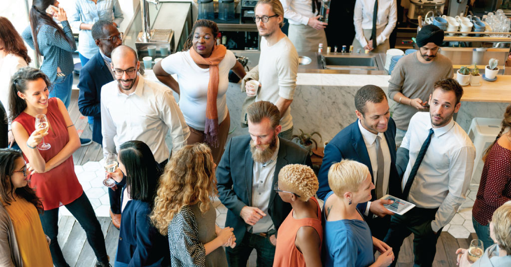 a group of adult professionals in business casual attire networking at an event