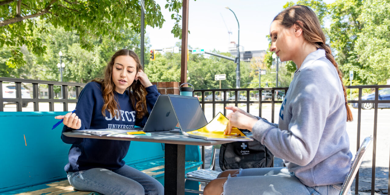 Two female nursing students studying outside at a picnic table