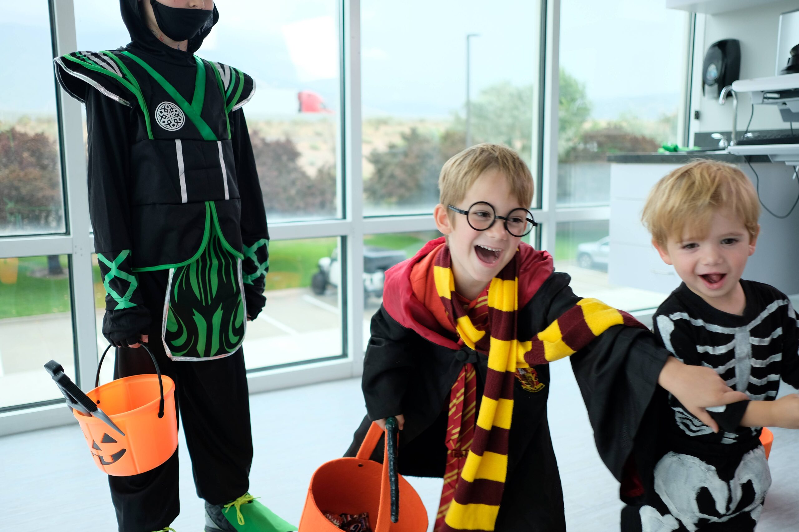 three boys in halloween costumes holding trick or treat buckets