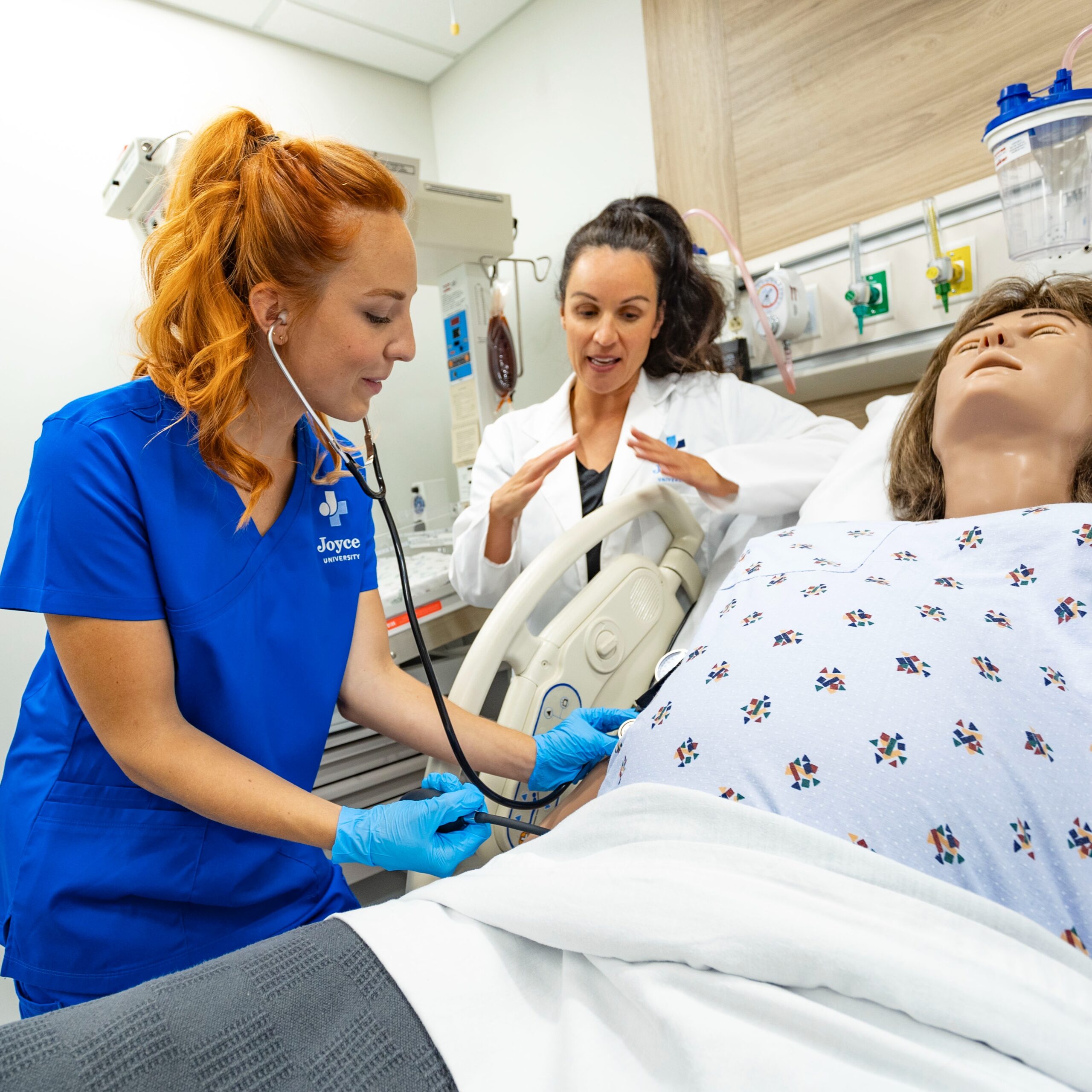 Joyce University student and faculty member training on a maternity patient simulator