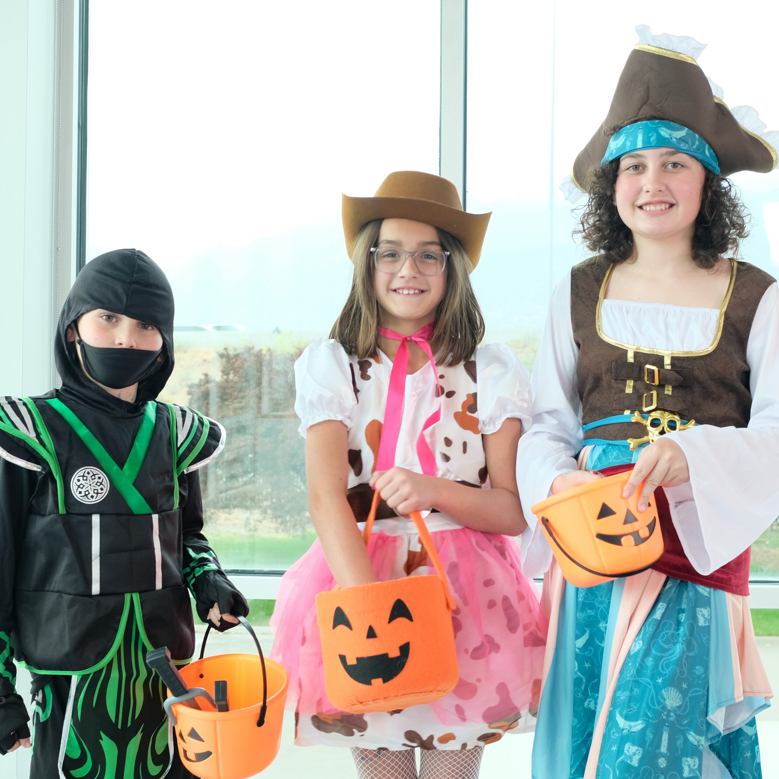 kids in halloween costumes holding trick or treat buckets