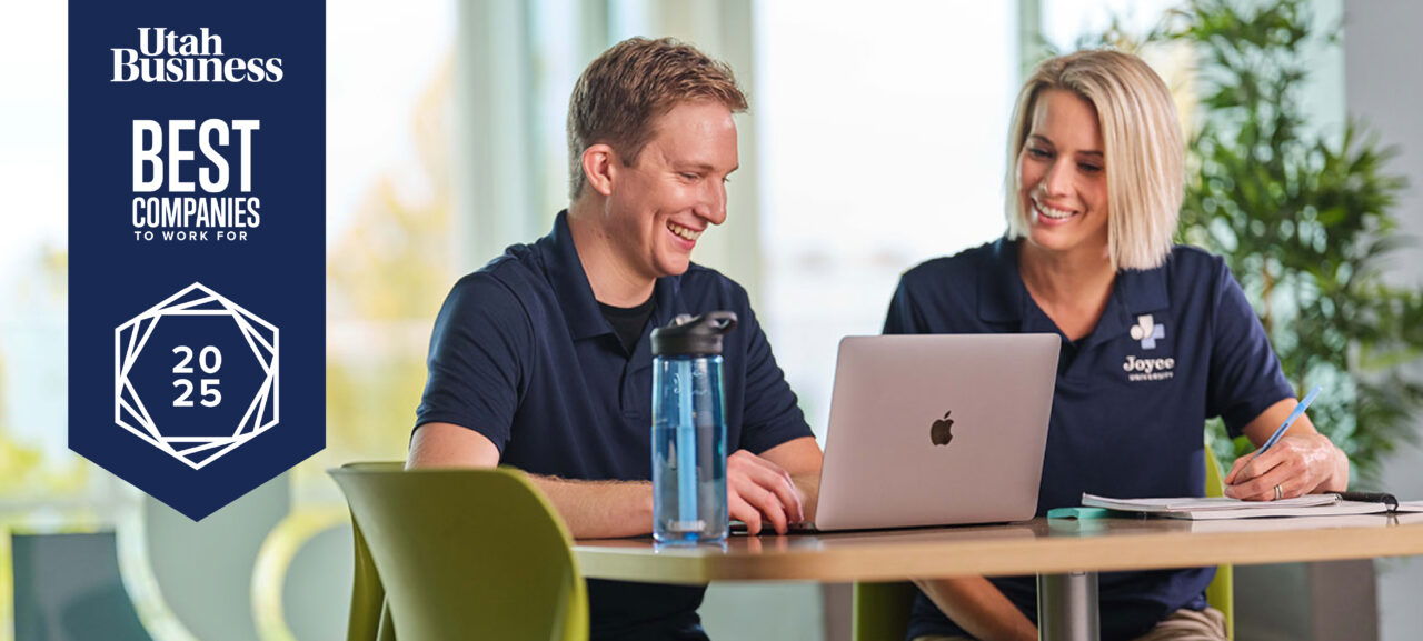 Joyce Awarded Utah Business 2025 Best Companies to Work For. Joyce team member and student smiling sitting at table with a laptop on campus.