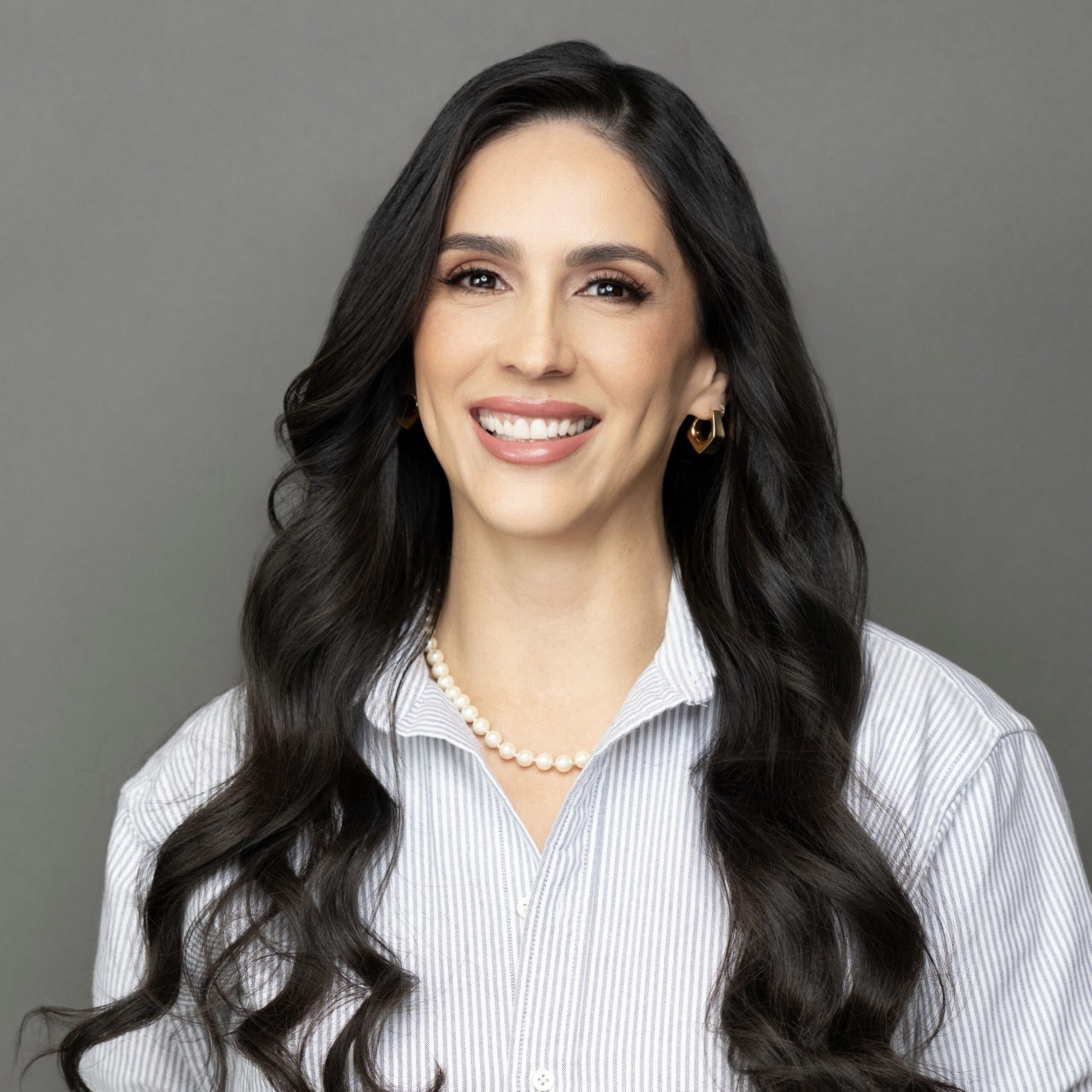 Ivette Matias VP of Clinical Operations & Business Development standing in front of grey background