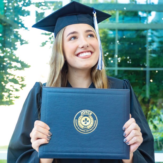 joyce university graduate in cap and gown smiling and holding diploma