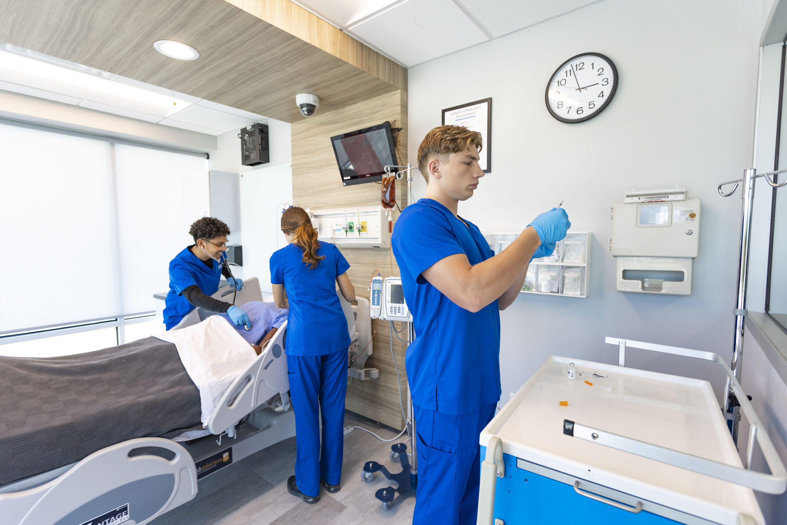 nursing students in sim lab practicing on mannequin