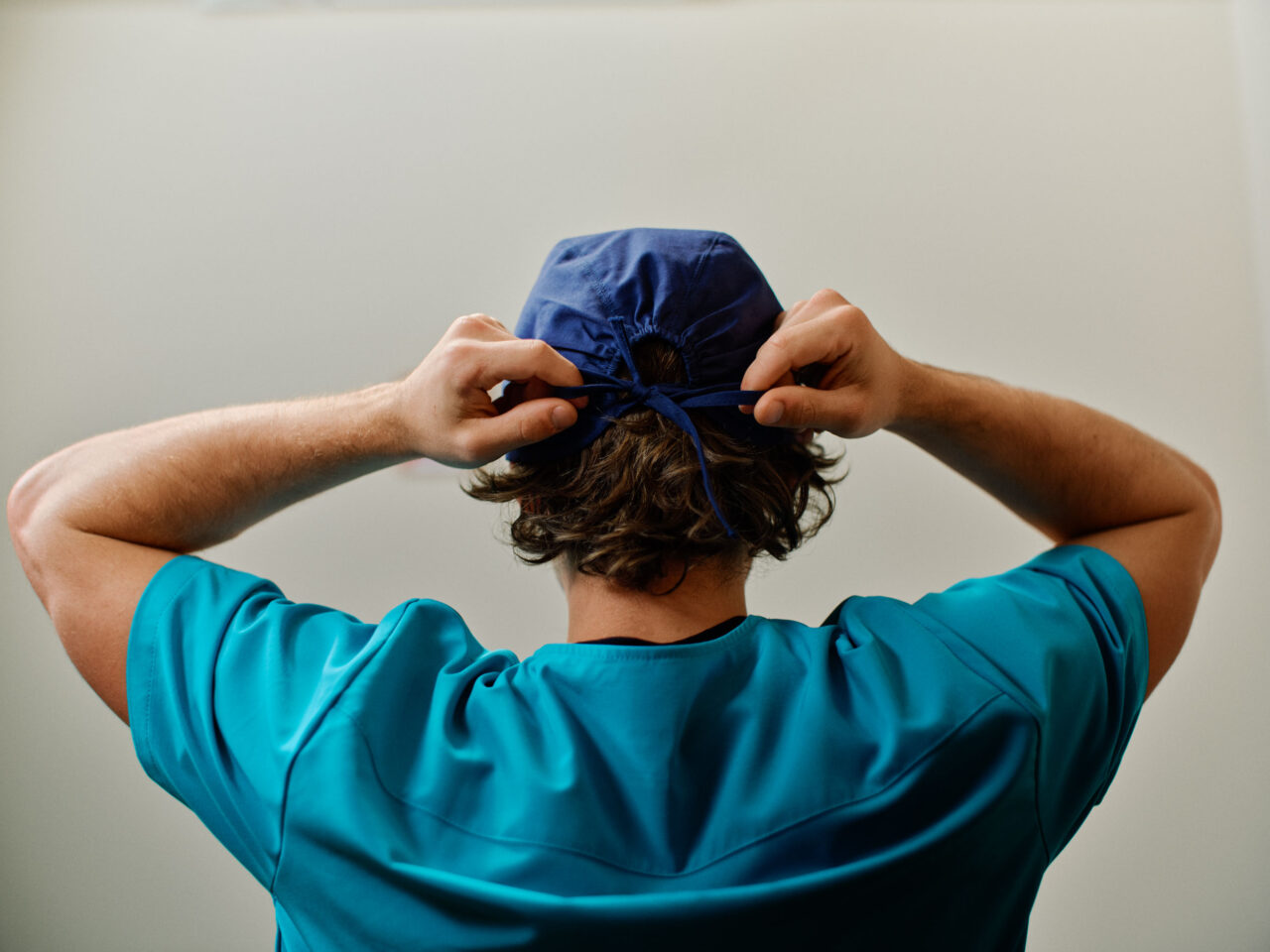 Nurse tying on scrub cap.
